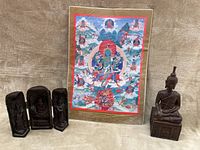 Photo of the carved wooden triptych altar panels, colorful Buddha Mandala thangka in plastic sleeve behind, and the small carved Buddha statue seated.