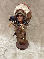 Front view of the detailed wooden Native American carving bust displaying the feathered headdress and facial details.