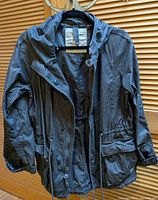 Front view of the TNA Griffith green military style women's jacket size small hanging on hanger with button and zipper closure, hood and flap pockets.