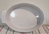 Top view photo showing the full oval shape and smooth white interior of the baking dish with handles visible.