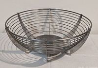 Stainless steel wire fruit bowl, side angle showing the shape and construction of the wire basket and supporting base.