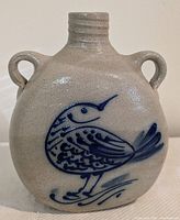Front view of the jug showing the two loop handles and the cobalt blue bird design on the front surface.