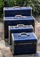 Four vintage navy blue marble Samsonite suitcases stacked outdoors on stone pavement