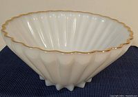 Side angled view showing fluted shape, pearl white color, and gold rim detail on the bowl.