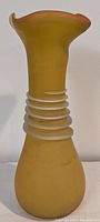 Side view of the amber-yellow scavo style art glass vase with spiral clear glass rings on the neck and flared wavy rim.