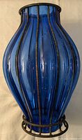 Front and side view of vintage cobalt blue blown glass vase enclosed in black wrought iron cage