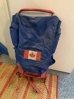Front view of the blue backpack with Canadian flag patch on front pocket showing some wear and dirt marks.