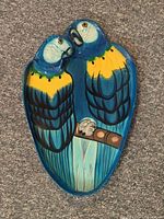 Full view of ceramic serving tray showing two blue and yellow parrots perched on a branch, highlighting the shape and vibrant colors of the tray.