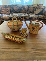 Four-piece set of hand-painted yellow Italian kitchen ceramics displayed on a wooden table with a patterned sofa in the background.