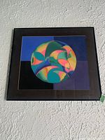 Full view of the framed geometric pastel wall art showing the black frame and colorful circular abstract design.