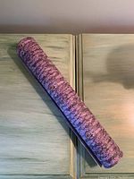 Image of rolled up lavender floral printed drawer lining paper placed on a wood surface.