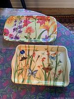 Photo showing two plastic trays with floral designs and butterflies, one medium rectangular and one smaller rectangular.