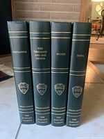 Spine view of the four hardcover books showing titles and Harvard crests.