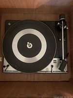 Top-down view of the Dual 1216 turntable showing the platter, tonearm, and control panel part of the unit with dust and minor wear visible.