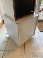 Bottom corner edge view of the white floor cabinet/stand showing clean sharp edges and overall condition.