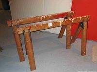 Front angle showing two wooden saw horses with paint splatters and sturdy construction.