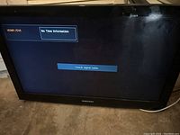 Front view of Samsung 32-inch TV powered on showing HDMI/AV input screen with 'No Time Information' message and scratches on screen.