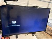 Front view of Avgo TV powered on showing 'No Signal' screen message. TV supported on table with wall mount attached.