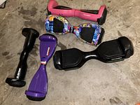 Photo showing five hoverboards on floor, including Voyager and Gotrax brands, in colors black, pink, purple, and multicolor pattern. Some wear and dirt visible.