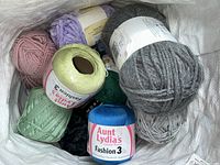 Bag containing various assorted yarn skeins and balls in multiple colors and textures.