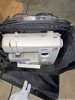 Top-down view of Brother sewing machine inside black travel case, showing machine, case interior, and part of handle.