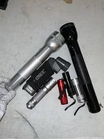 Seven flashlights of various sizes and types arranged on a surface including two large metal flashlights and five smaller ones of different colors and styles.