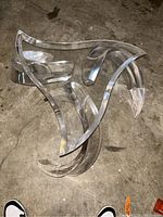 Sculptural Lucite base of the mid-century coffee table seen from above on concrete floor.