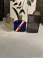 Three men's cologne bottles on a flat surface with a floral background.