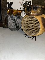 Two metal owl figurines shown from front, one decorative mesh owl and one electric owl heater.