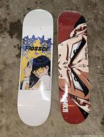 Photo showing two new skateboard decks side by side, each with distinctive graphic prints on the topside.