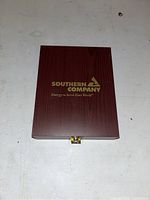 Closed wooden box with Southern Company logo in gold on top.
