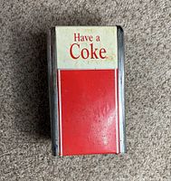 Front view of the vintage napkin dispenser with 'Have a Coke' text and red and white design.