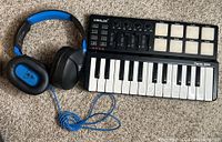 Front view of Turtle Beach headphones and Worlde Panda Mini MIDI keyboard controller on carpet