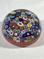Top view of the round glass paperweight showing detailed colorful millefiori flower patterns under clear glass.