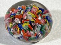 Close-up of the round paperweight showing colorful millefiori fragments encased in clear glass.