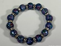 Full view of bracelet laid flat, showing round glass beads and silver-tone spacers.