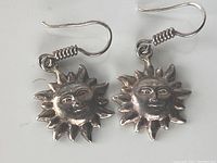 Front view of the sterling silver sun face earrings showing facial details and sunburst pattern in silver metal.