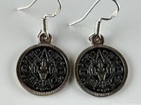 Pair of sterling silver circular dangle earrings with Mayan calendar detail shown laying flat to show both sides and hooks.