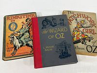 Three vintage Oz books by L. Frank Baum including Rinkitink in Oz, The Patchwork Girl of Oz, and The Wizard of Oz, showing front covers and condition.