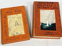 Two vintage hardcover Doctor Dolittle books by Hugh Lofting with orange illustrated covers.