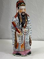 Front view of the 15-inch tall porcelain figure of a Chinese man representing Wisdom, showing the detailed traditional robes, facial features, and the scroll held in his hand.