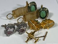 Two pairs of cuff links and one tie pin shown together on a white background.