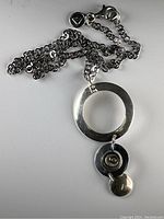Full view of silver chain necklace with modernist circular pendant showing chain length and overall design.