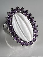 Front view of the vintage style sterling silver ring showing the large oval white carved centerpiece surrounded by lavender crystals.