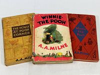 Three vintage A.A. Milne Winnie The Pooh books displayed side by side with cover art visible.