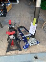Image showing blue and silver hydraulic floor jack alongside two black metal jack stands with red locking handles.