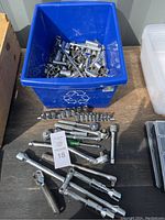 Photo showing blue bin filled with various sockets and a collection of ratchets, sockets, and extensions displayed in front.