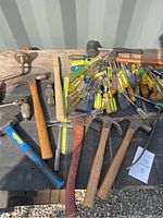 Multiple hand tools including hammers, screwdrivers, vintage brace drill on wooden surface