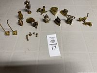 Full view of lot of 17 assorted brass miniatures laid out on table including animals, household items, and collectibles