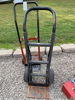 Front view of two hand trucks with black and orange frames, showing tires and toe plates.